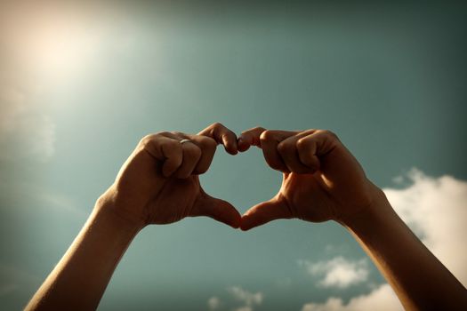 Toned Photo of Hands in Heart Shape on Sky Background