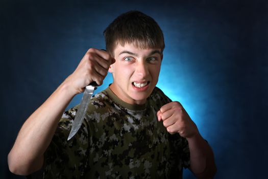 Angry Teenager with Knife On the Dark Background