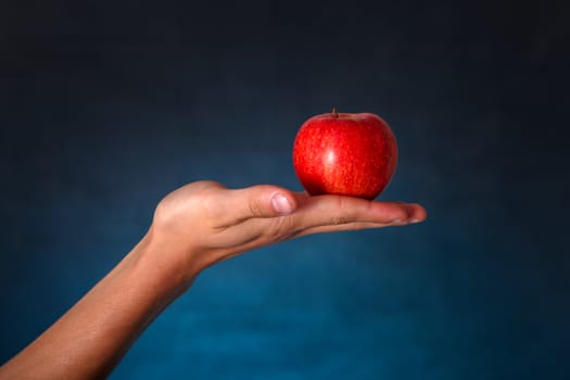 Hand with Red Apple on the dark background