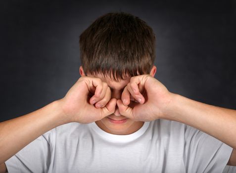 Young Man Rub his Eyes on the dark background