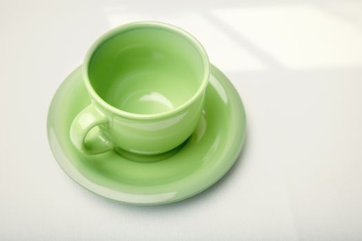 Green teacup on a table with shadow