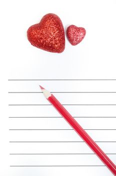 Red pencil and two hearts on a blank love letter