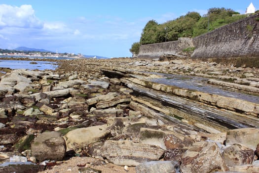 rocks by the sea at low tide on an ocean horizon and mountains