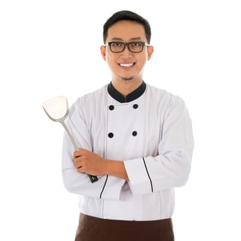 Portrait of Asian chef holding spatula, smiling and standing isolated on white background.