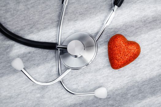 Stethoscope and heart symbol on a table with shadows