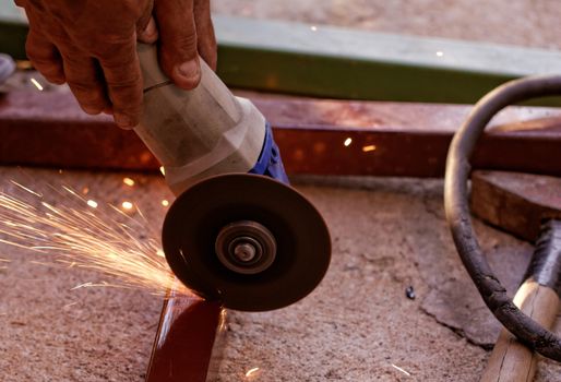 Metal sawing with hand grinder. Sparks while grinding iron.