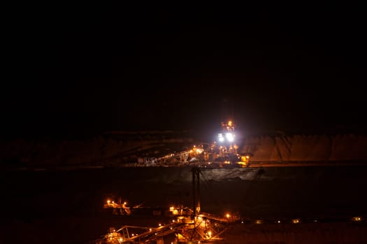 Coal mining in an open pit with huge industrial machine at night shoot