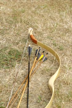 color archery arrows and bow in nature on the ground