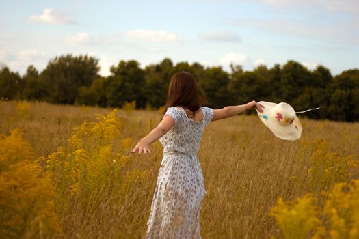 Portrait of beautiful young woman with flowers in the field