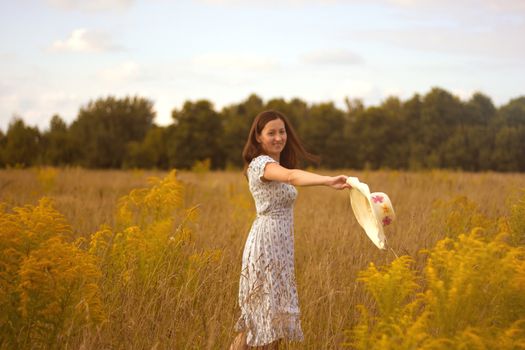 Portrait of beautiful young woman with flowers in the field