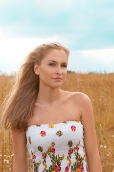 Portrait of beautiful young woman with flowers in the field