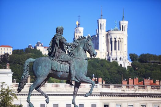 Famous statue of Louis XIV and Basilique of Notre Dame de Fourviere on a background 