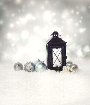 Christmas lantern and ornaments on the snow in a silver shinning night