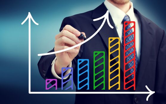 Businessman drawing a rising arrow over the colorful bar graph