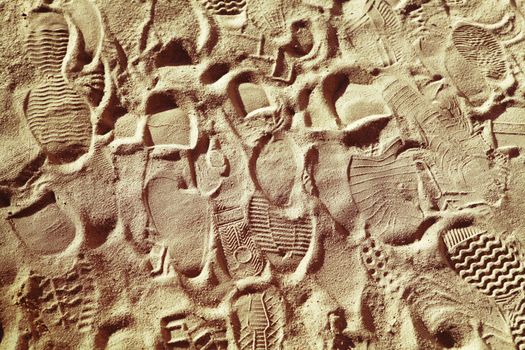 prints from various footwear on sand, background