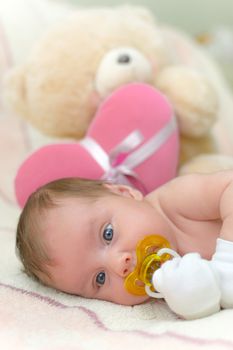 Infant baby (1 month old) lying on bed with teddy bear