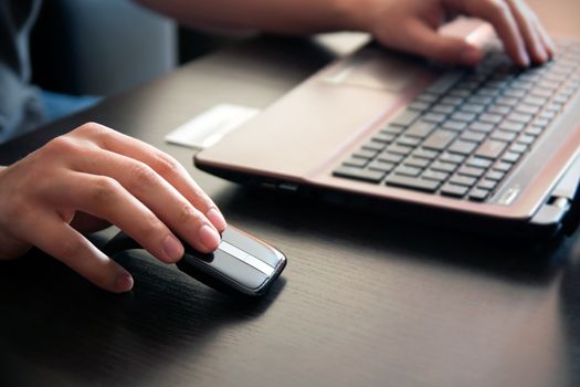 Human hand on computer mouse. Laptop on desk.