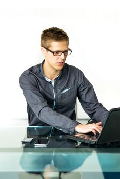 Young businessman sitting at table, working on laptop. 