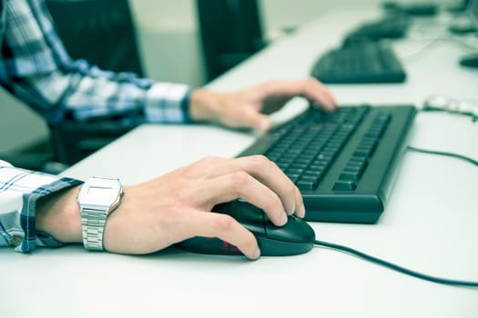 Young man typing on keyboard. Training room with computers