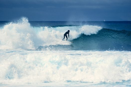 Surf-rider on a large blue ocean wave