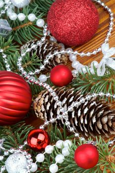 Spruce Branch and Fir Cones with Red and Silver Baubles, Bows, Pearl and Silver Beads closeup on Wooden background