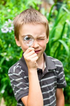 Young boy looking through hand magnifier outdoors