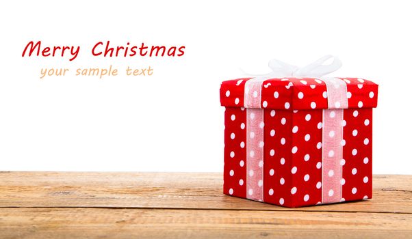 Red gift box with white ribbon on wooden, on white background.