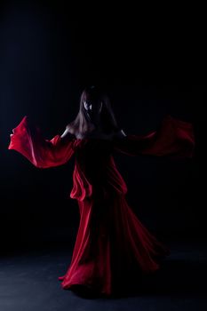 Young girl in red dancer in a darkness

