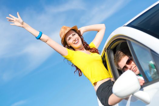 young attractive woman in sunglasses got out of the car window and laugh