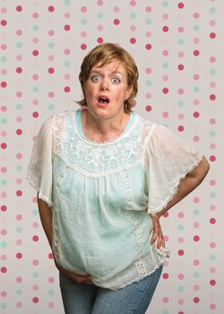 Startled pregnant woman on polka dot background