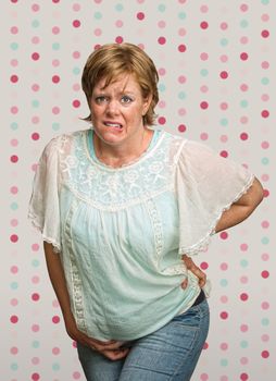 Uneasy pregnant woman with pains on polka dot background