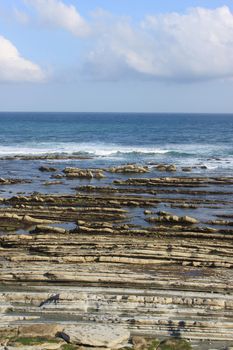 rocks and an ocean at low tide under a blue sky