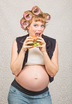 Happy female hillbilly in curlers eating a sandwich