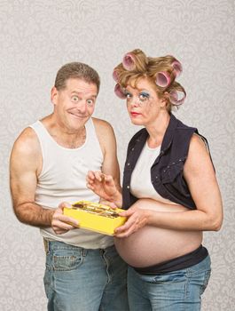 Guilty pregnant woman eating candy with smiling man