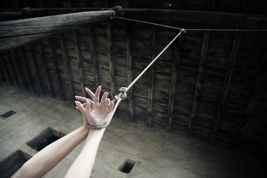 Woman hands hanged on the rope in ancient exterior