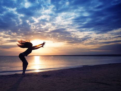 Dancing dynamic woman at the beach during sunset