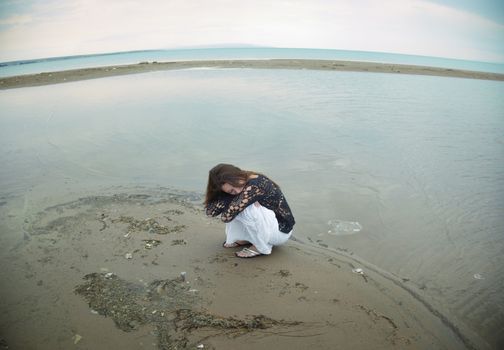Single vulnerable woman sitting on small island within the water. Fish-eye photo