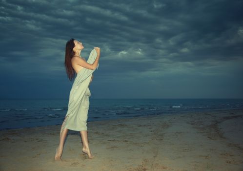 Nifty lady covered by towel standing at the night beach