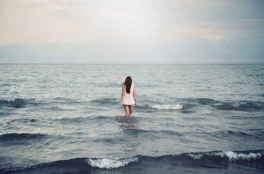Rear view on a single lady going into the sea. Horizontal photo