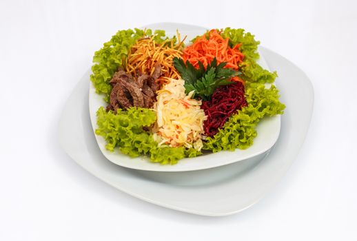 Fresh vegetable salad with slices of meat, filmed on a sheet of white plastic, close-up