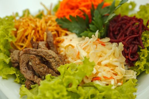 Fresh vegetable salad with slices of meat, filmed on a sheet of white plastic, close-up