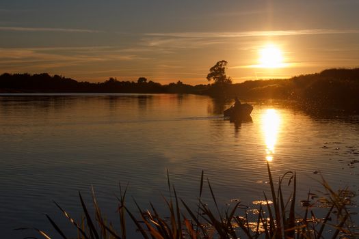 Sunset on the river. A lone fisherman in a boat