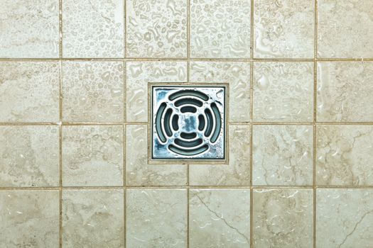 Metal drain hole in the tiled floor of a shower