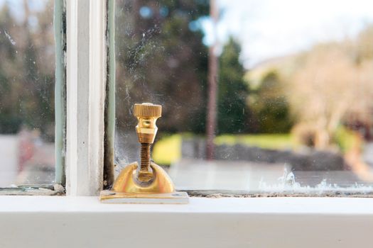 Brass screw lock on an old fashioned window in a house