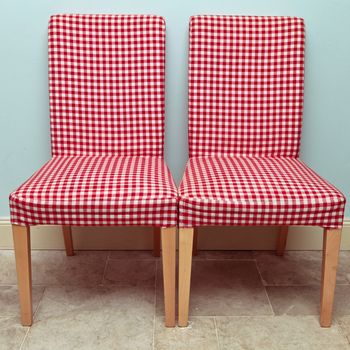 Pair of gingham covered dining chairs against a blue wall