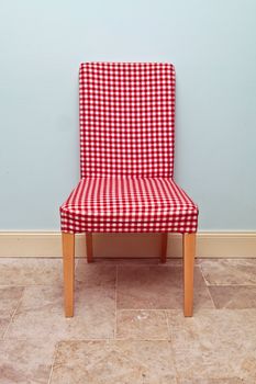 Single gingham covered dining chair against a blue wall