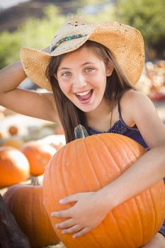 Preteen Girl Holding A Large Pumpkin at the Pumpkin Patch in a Rustic Setting.