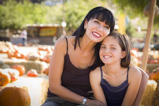 Attractive Mother and Baby Daughter Portrait in a Rustic Ranch Setting at the Pumpkin Patch.
