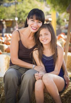 Attractive Mother and Baby Daughter Portrait in a Rustic Ranch Setting at the Pumpkin Patch.
