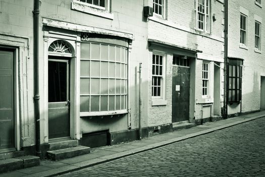 Buildings on a cobbled street in England in sepia tones